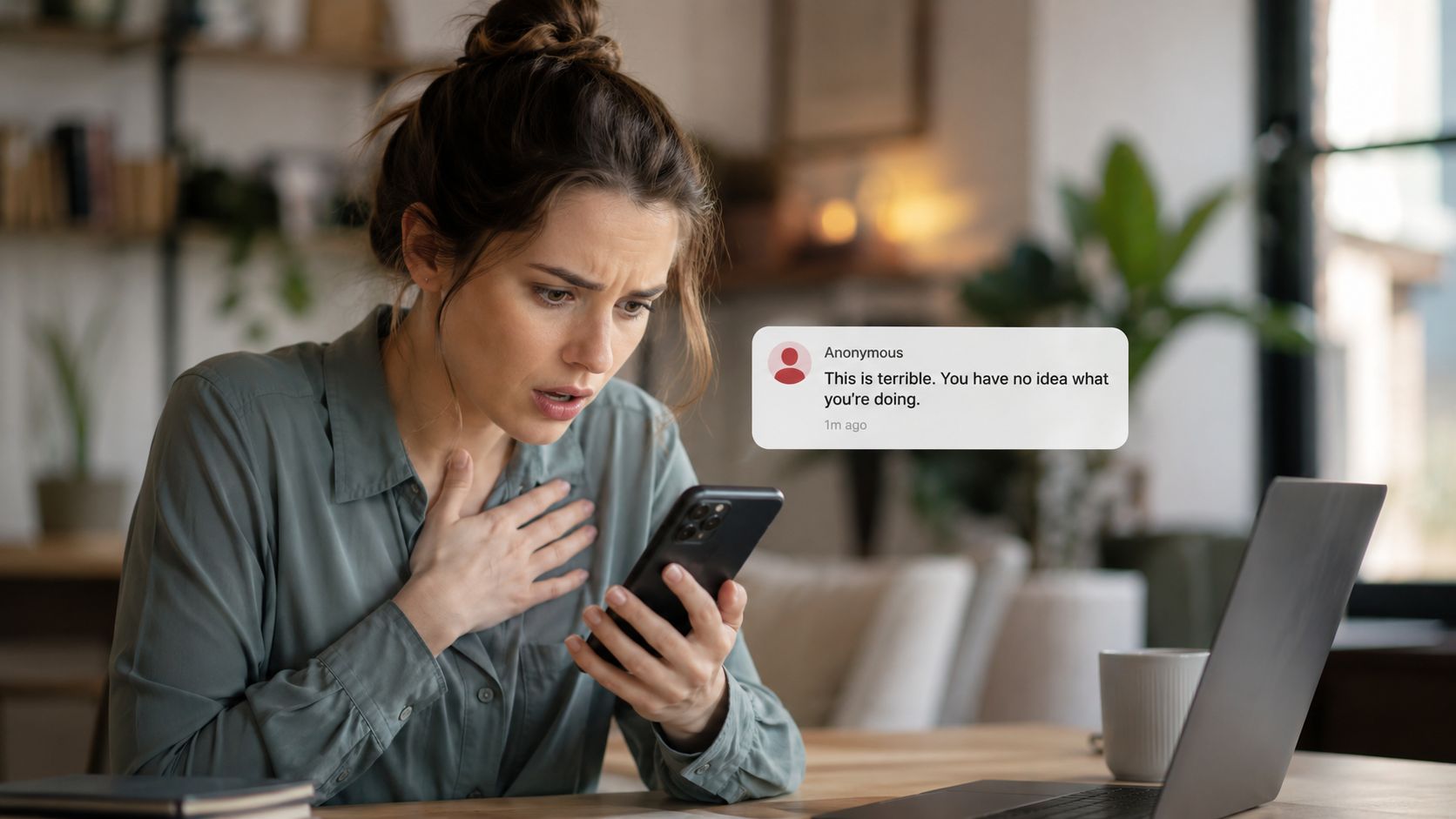 A woman looks distressed and anxious while reading a harsh anonymous message on her mobile phone screen.